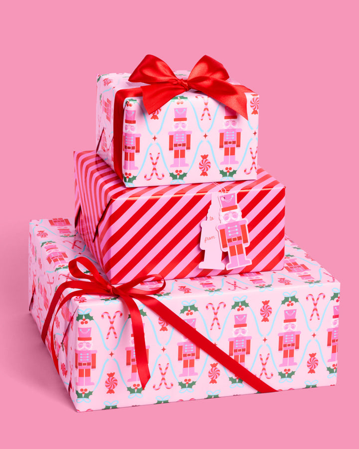 Christmas presents wrapped in pink and red nutcracker paper and candy stripe, topped with a red bow.