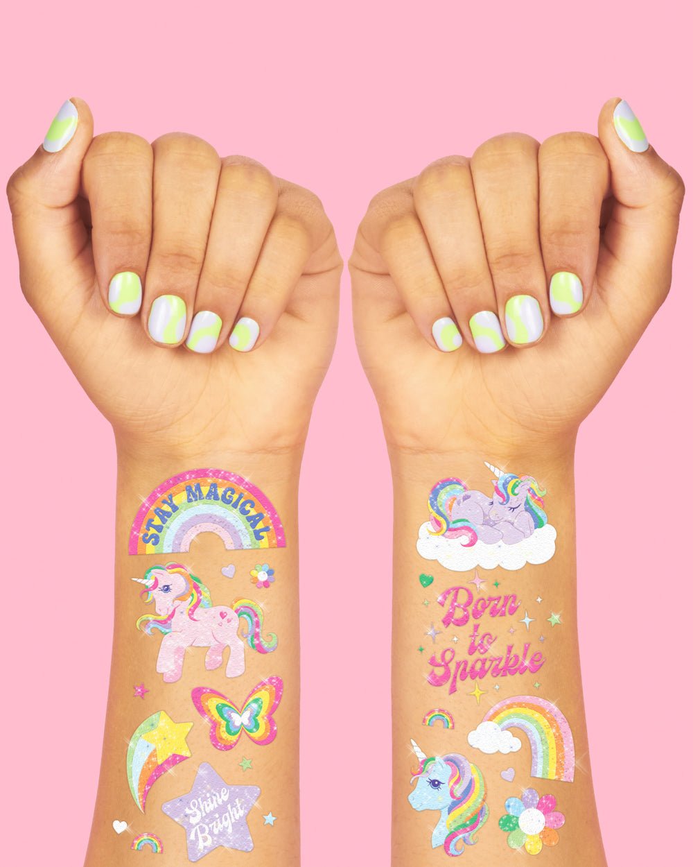 Two arms wearing unicorn temporary tattoos: Stay Magical rainbow, unicorn on a cloud, butterfly, and Born to Sparkle