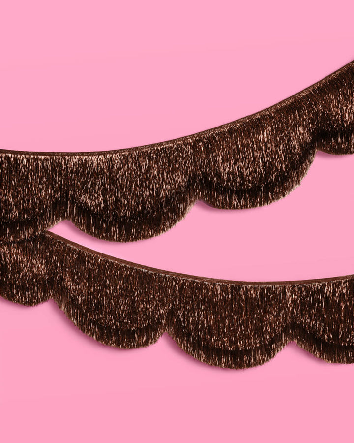 Espresso brown scallop fringe banner with two layers of shiny foil fringe on a pink wall