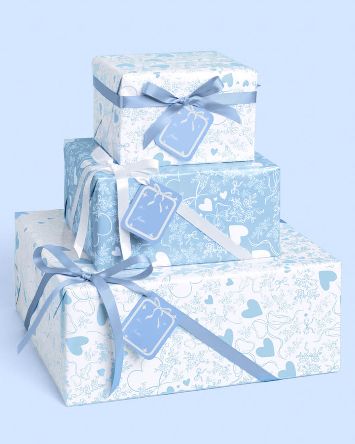 Wedding gifts wrapped in powder blue paper with hearts, florals, and bows, tied with pale blue satin ribbon.