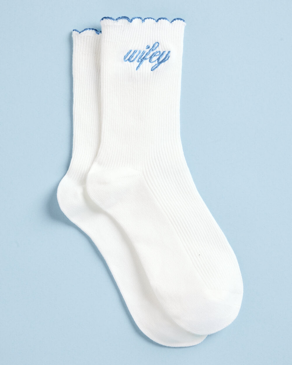 Wifey bride socks in white rib knit with light blue script embroidery and scalloped blue cuffs on pale blue