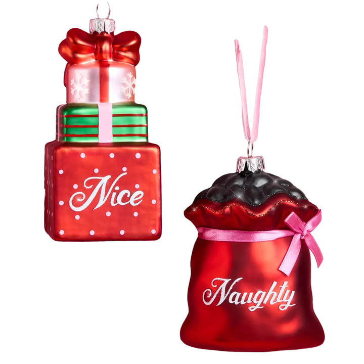Set of two glass Christmas ornaments, a red Naughty coal sack and a Nice stack of gift boxes, both hanging from pink velvet ribbons.