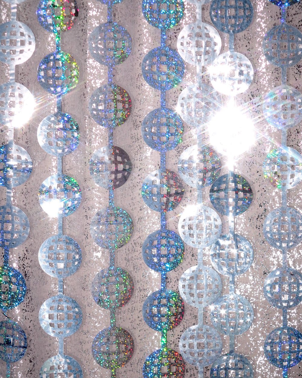 Iridescent silver disco ball foil curtain strands hung outdoors as a party backdrop