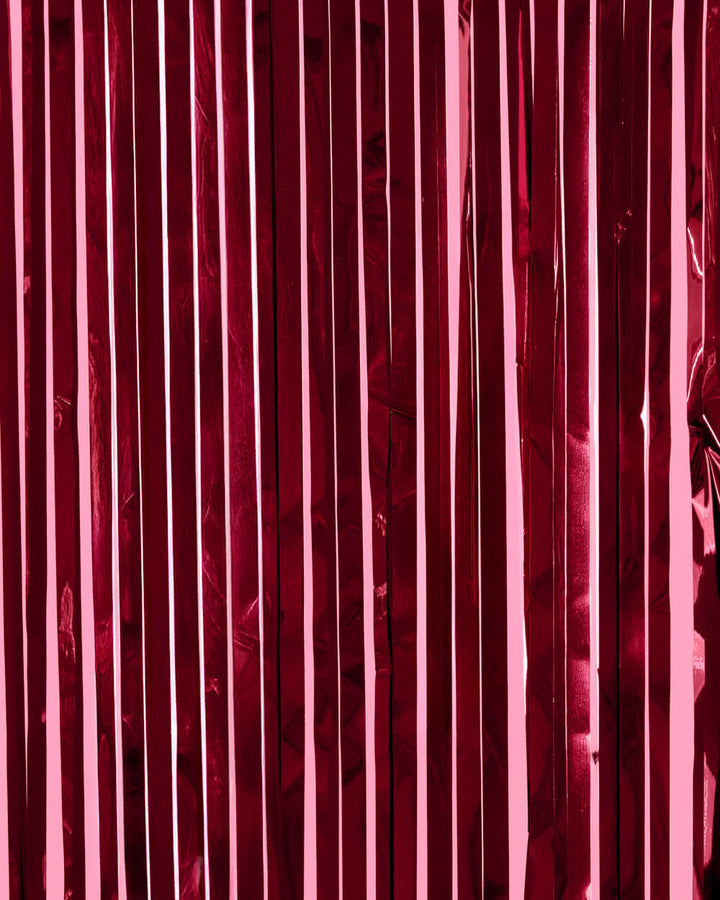 Burgundy metallic foil fringe curtain hung full width as a deep wine party backdrop