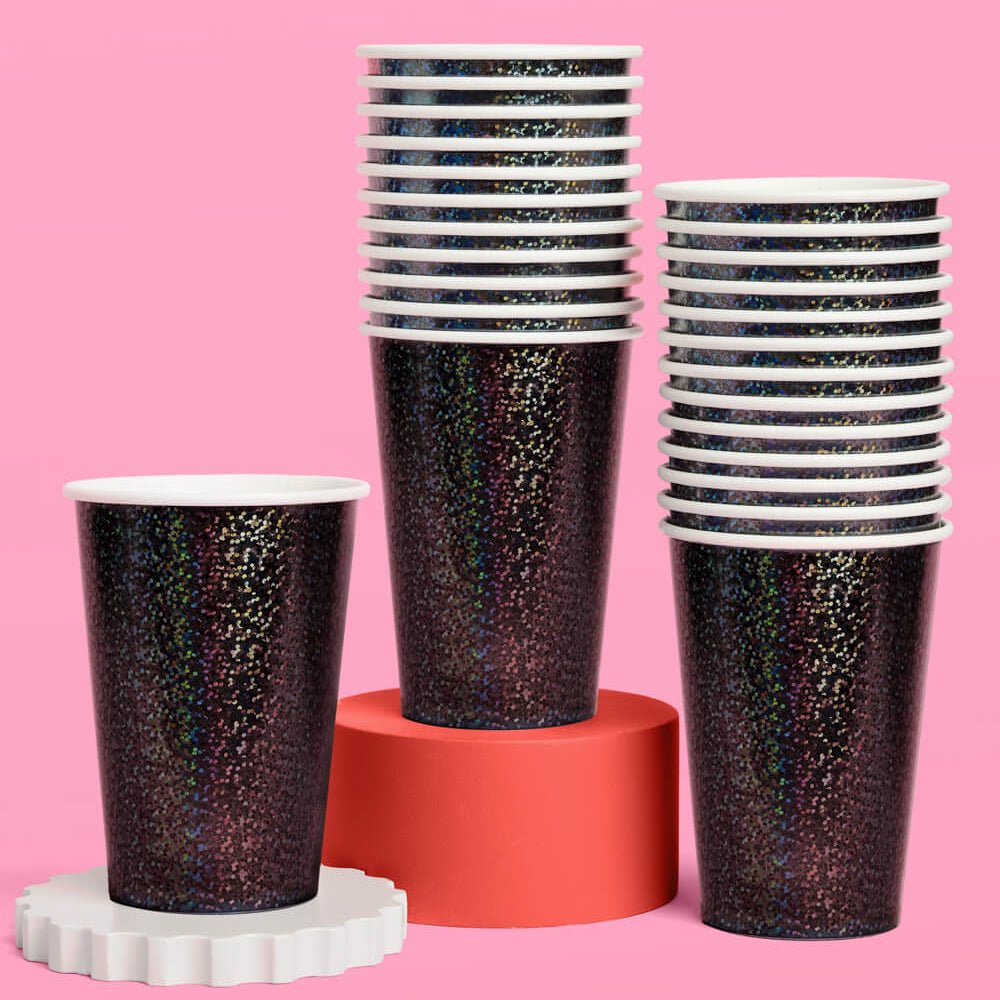 Stacks of black iridescent foil paper cups displayed on pink and cream risers