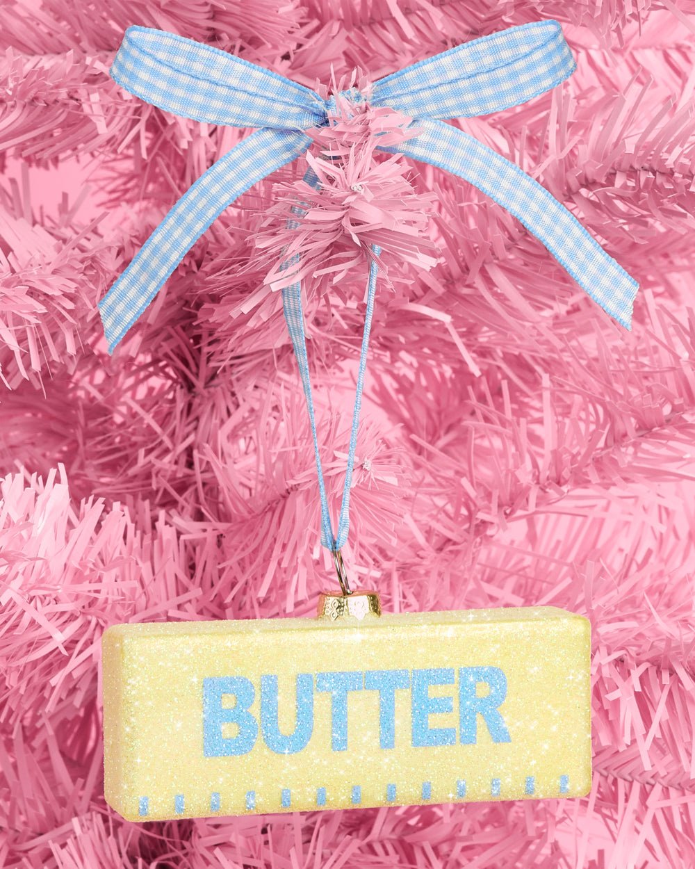 Yellow glitter glass butter stick ornament with a blue gingham bow on a pink tree