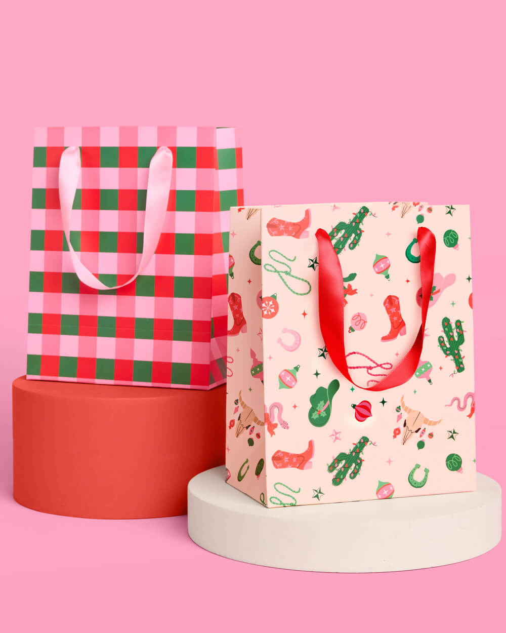 Western Christmas gift bags in red and green gingham and cream cowboy print, with red satin ribbon handles.