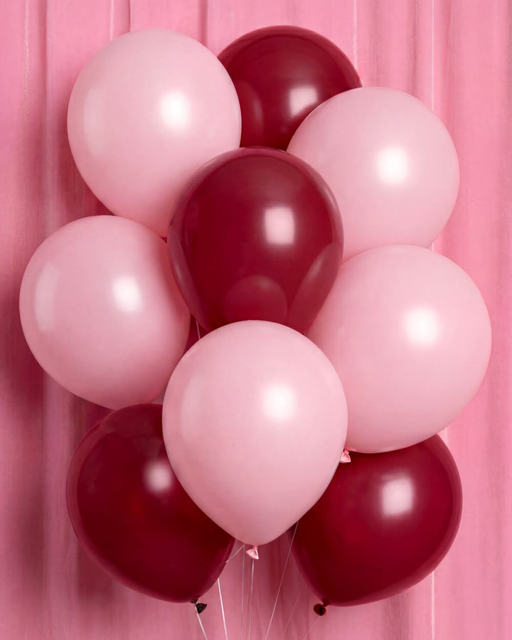 Bunch of burgundy and soft pink latex balloons against a pink backdrop