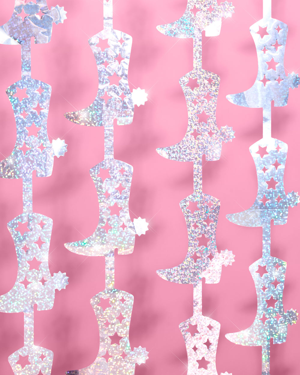 Iridescent glitter cowgirl boot foil curtain hung as a western party backdrop against a pink wall