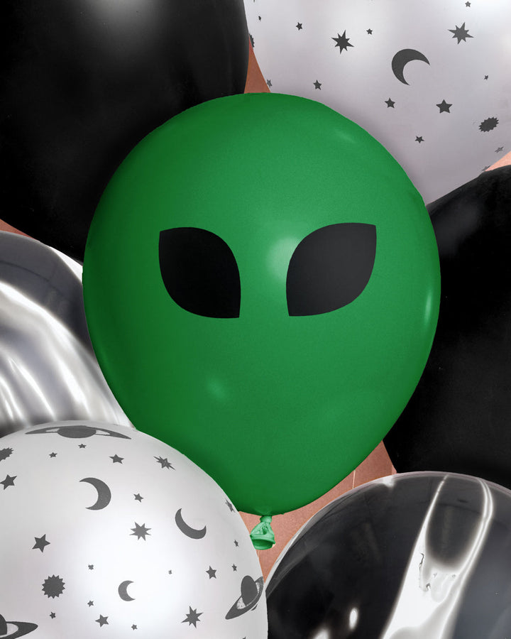 Close-up of a green alien face latex balloon among black and silver space-print balloons