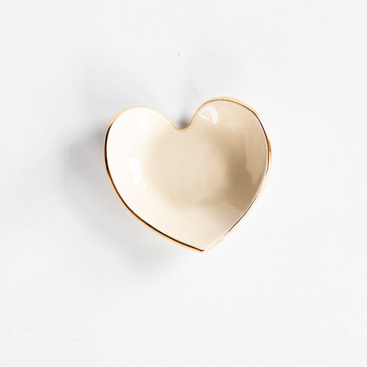 Warm taupe heart ring dish with a gold rim, angled view