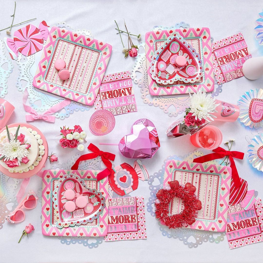 Overhead Valentine's party table with velvet bows, heart plates, and a red tinsel wreath