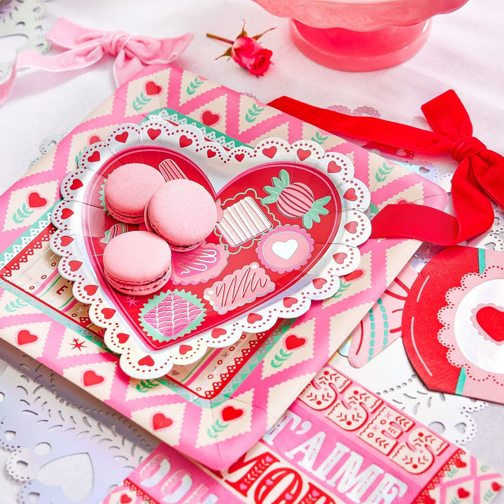 Red velvet bow clipped to a pink heart tray of macarons on a Valentine's table