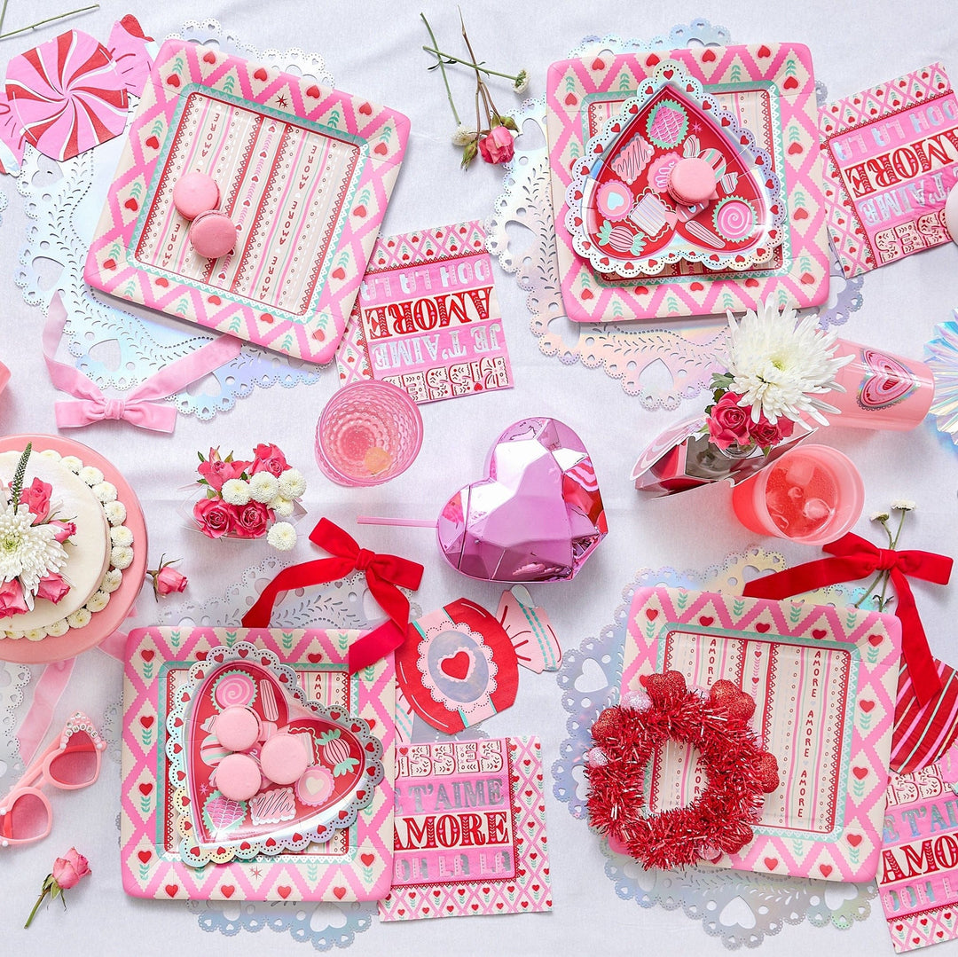 Valentine's table flat lay with red velvet bows, heart trays, candy, and pink heart cups