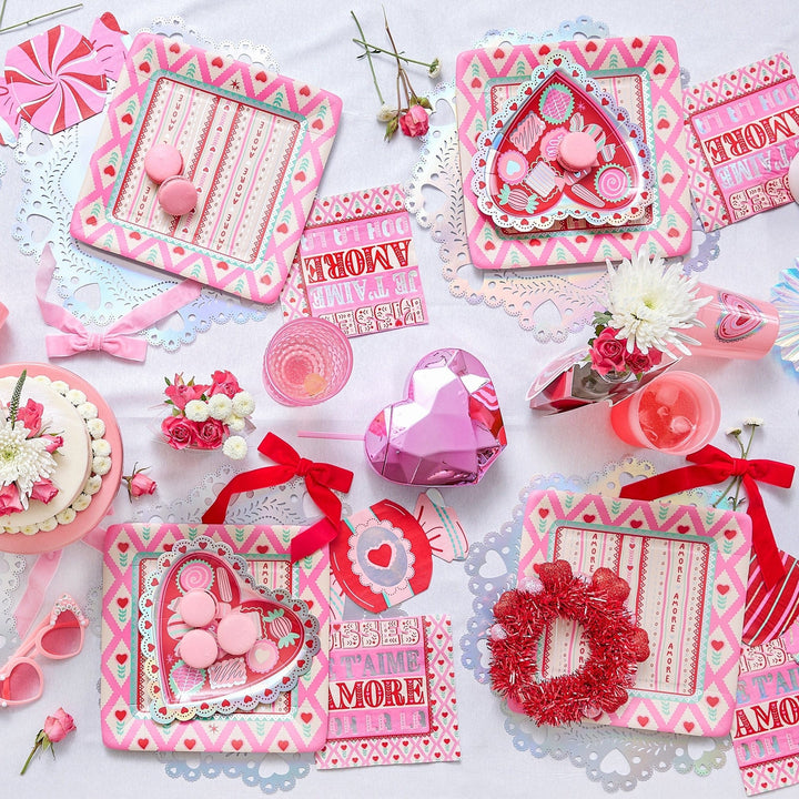 Valentine's table flat lay with red velvet bows, heart trays, candy, and pink heart cups