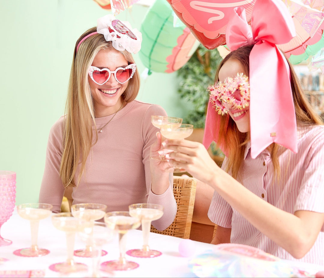 Twelve champagne coupes and pink pong balls for a game of champagne pong