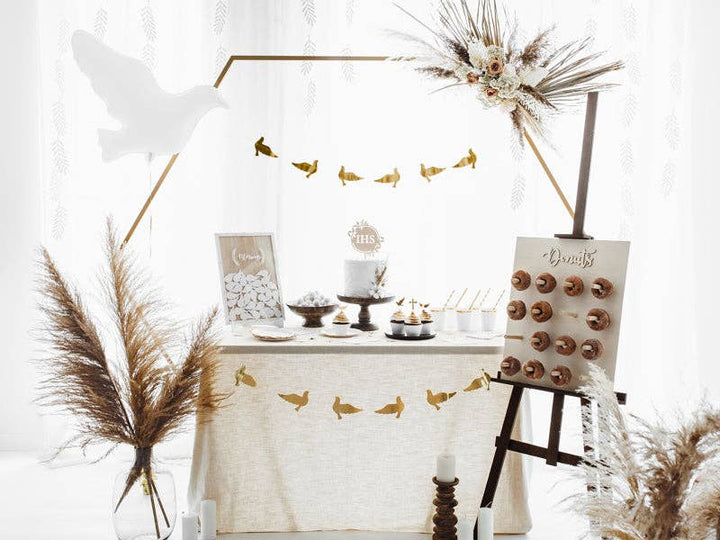 White dove balloon over an ivory and gold first communion dessert table with pampas grass