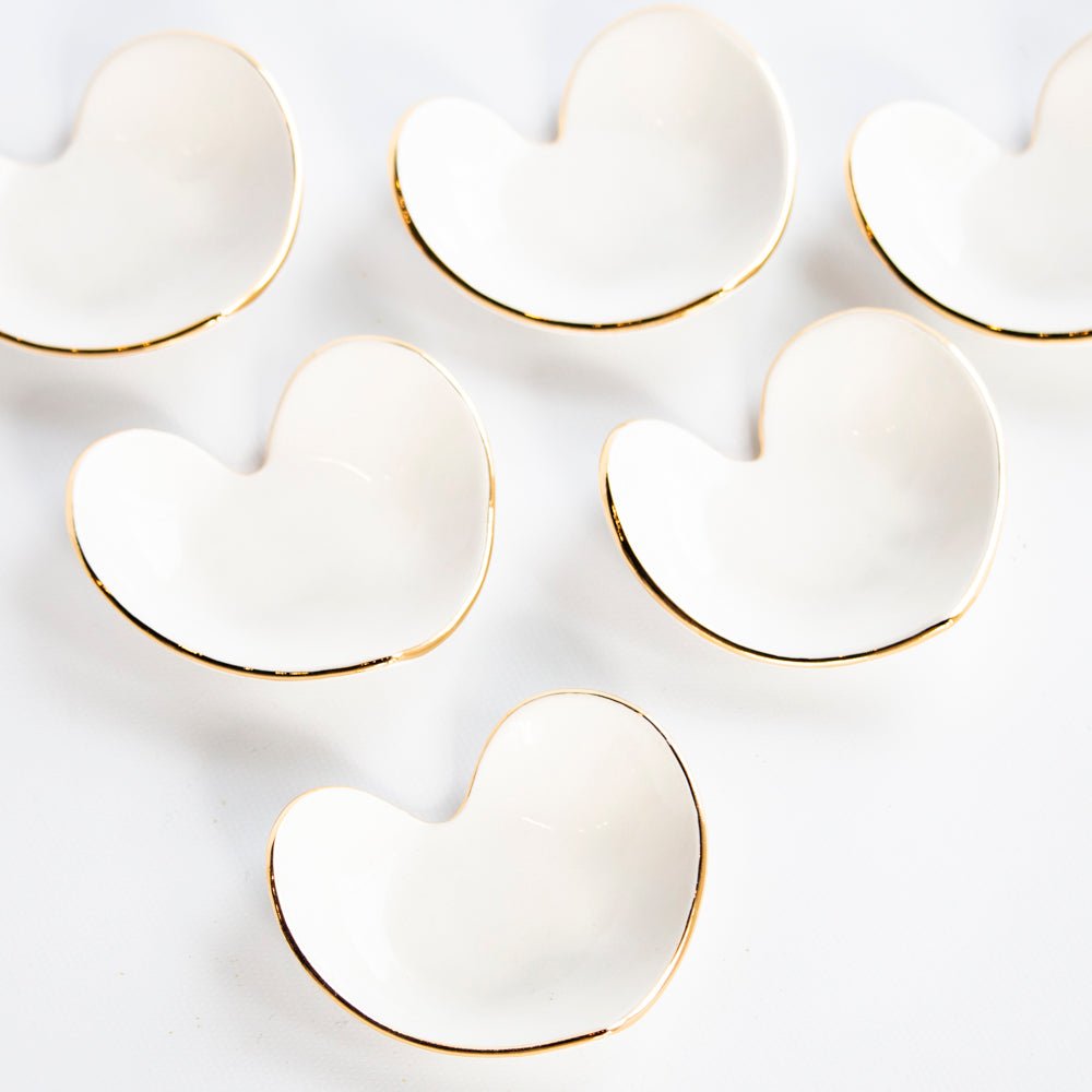 Cluster of white heart ring dishes with gold rims, overhead view