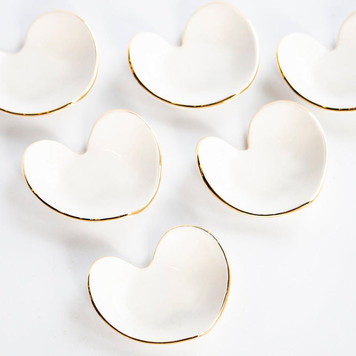 Cluster of white heart ring dishes with gold rims, overhead view