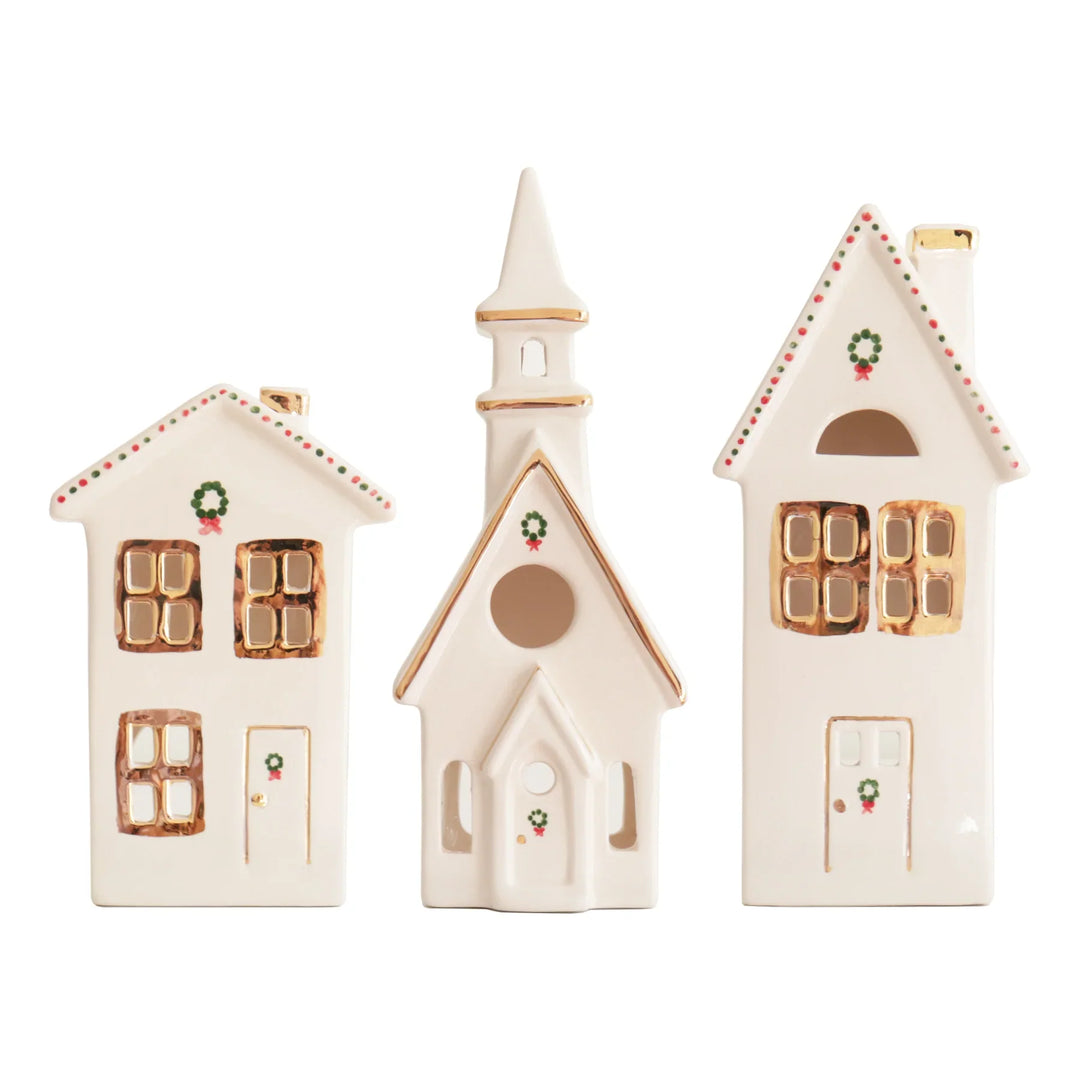 Ivory ceramic Christmas village of two houses and a church with gold trim windows and tiny green wreaths