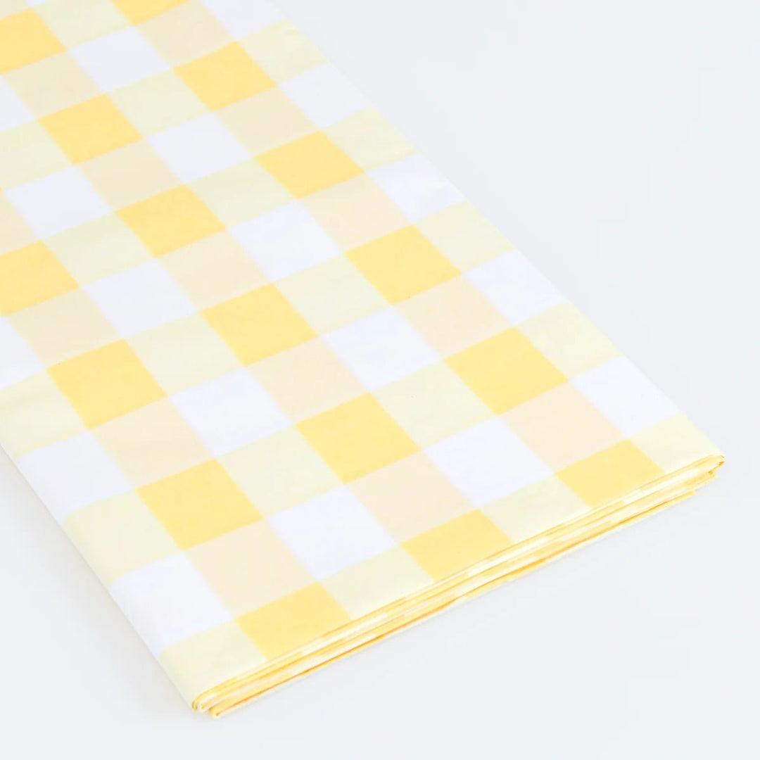 A folded piece of paper tablecover with a yellow and white gingham checkered pattern, displayed on a clean white background.